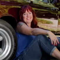 A woman sitting on the ground next to a car.