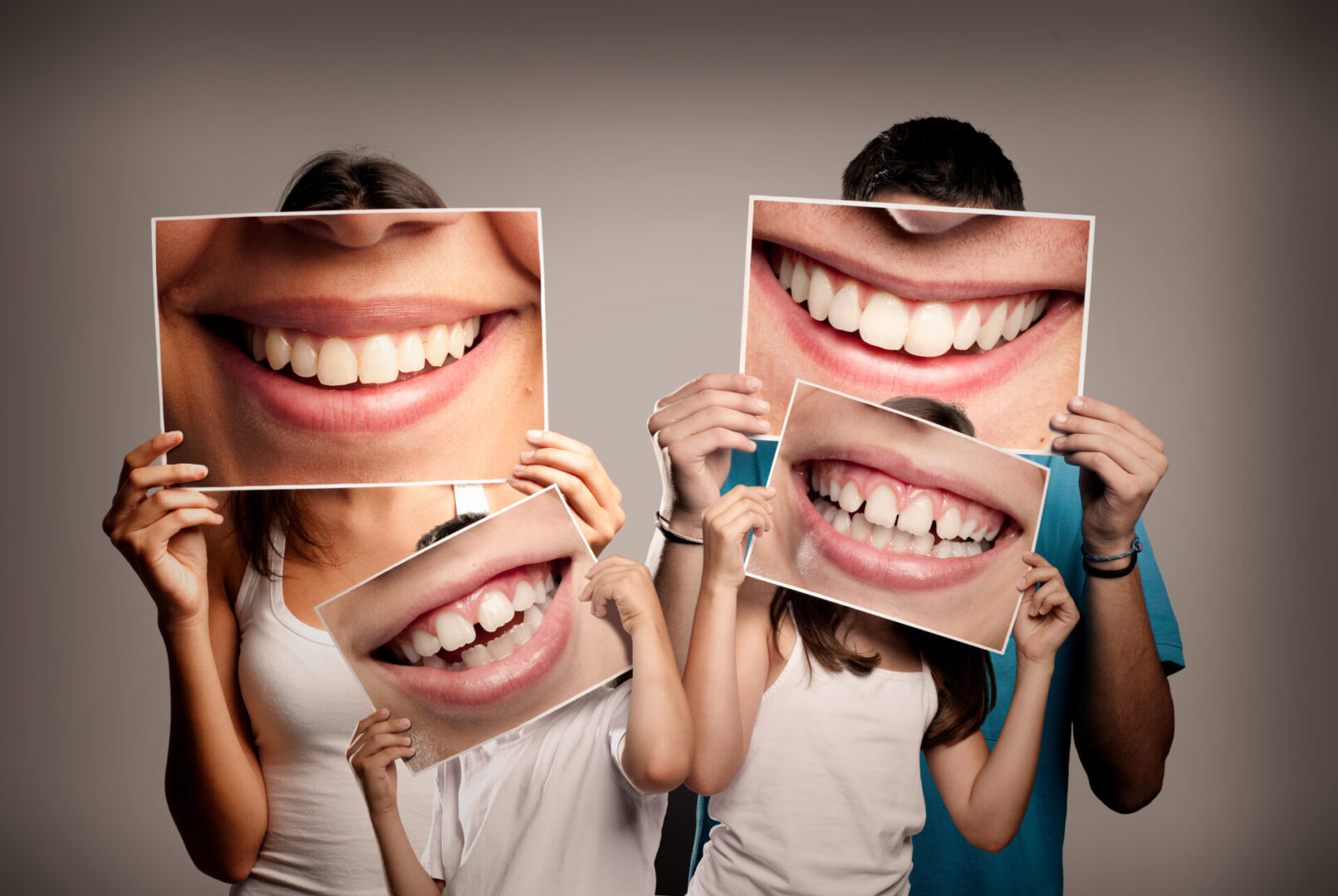 Three people holding up pictures of their smiles.